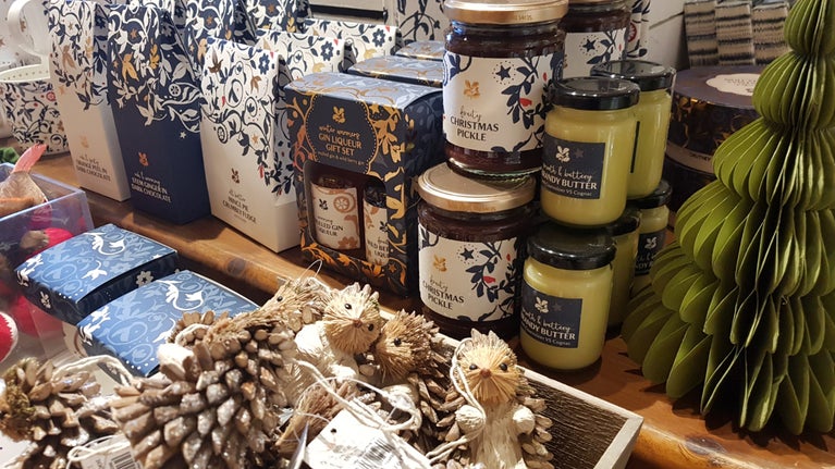 A close up picture of a display table in the shop at Wightwick, with a range of Christmas decorations and food, such as brandy butter and pickles.